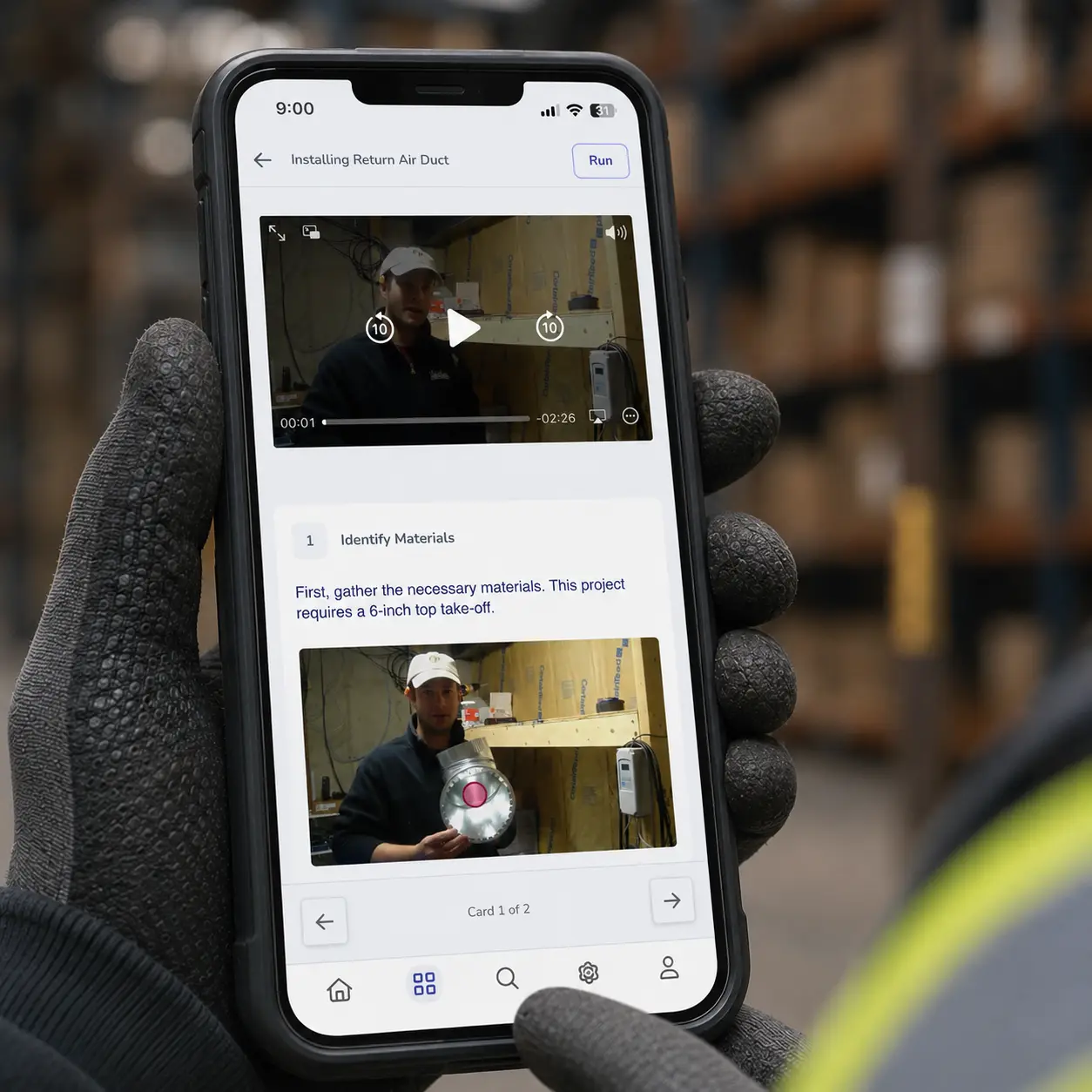 A gloved hand holding a phone with a Whale procedure open on the warehouse floor